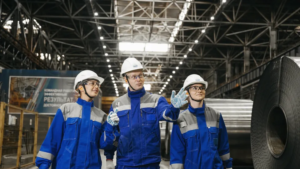 Trainees in blue protective gear inside a processing plant